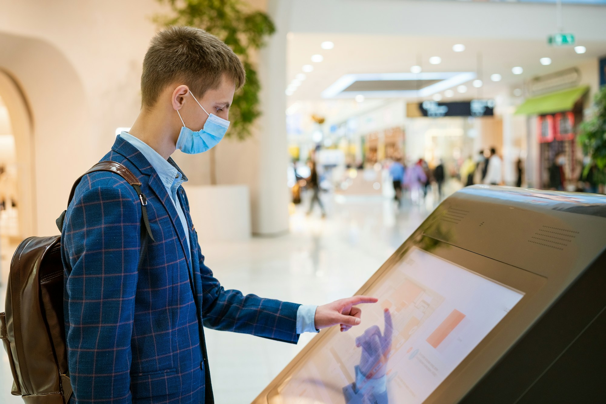 young man in a shopping mall looks at the monitor in a mask, the concept of internet searc